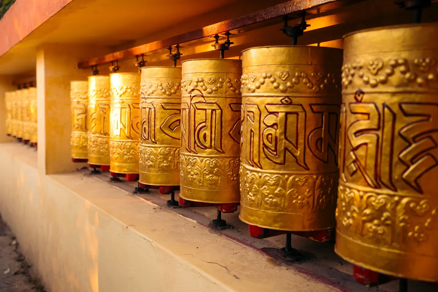 Row of golden prayer wheels with Tibetan script