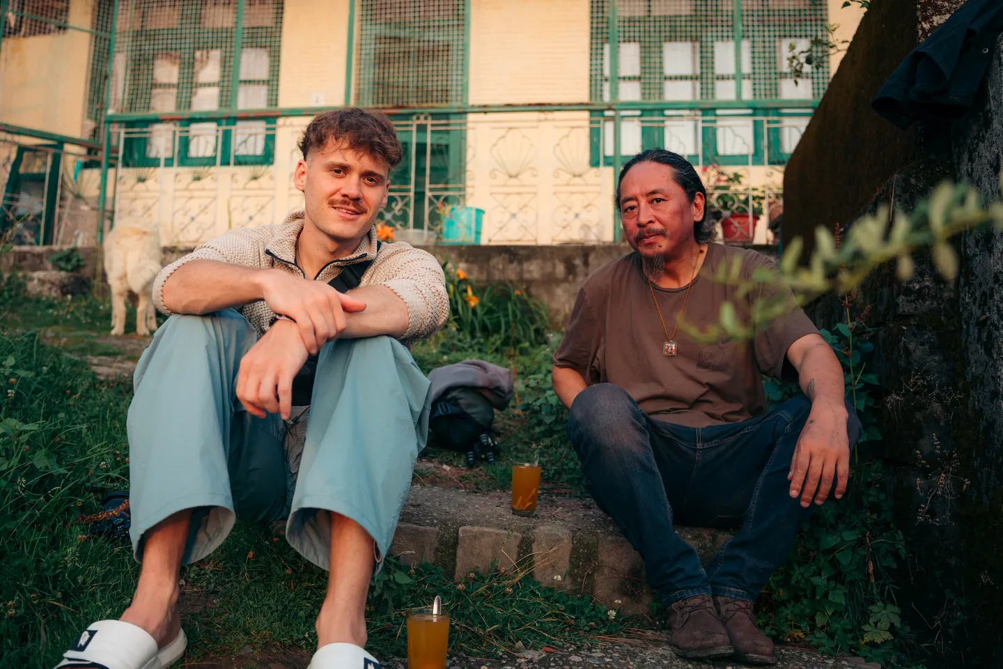 Jigme Namdol sitting on the steps of a house in Dharamshala with TOTO Studio